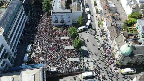Eddie Mitchell An aerial view of thousands of people crowding a busy street. 