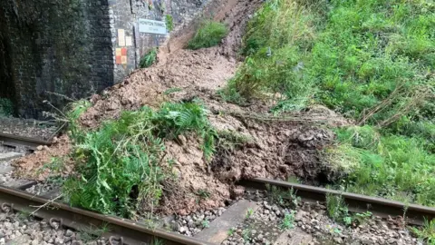 Network Rail Wessex Blocked train line between Axminster and Honiton. A large amount of mud and debris is on the line in front of a tunnel