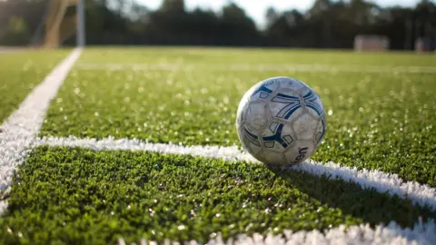 A football field with a ball placed on the arc area of the corner spot.