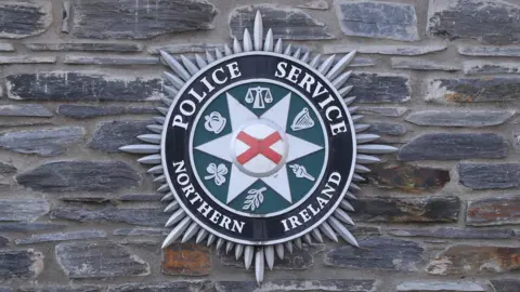 PA Media PSNI logo on a stone wall 