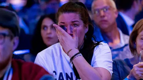 A conservative supporter dries tears from their eyes surrounded by other members of the crowd looking disappointed, after it was announced that Mark Carney won the general election, at an election night event in Ottowa on 28 April