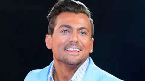 PA Paul Danan smiling in a turquoise suit