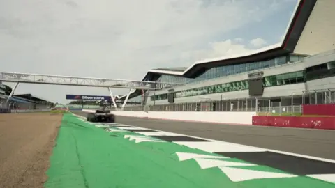 Apple Original Films/Warner Bros A still of the F1 trailer of a race car going down the Silverstone Circuit straight