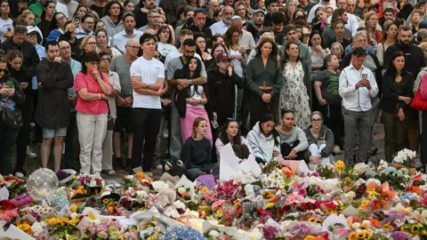 Getty Images Mourners surround a major flower tribute for the victims of the Bondi attack.