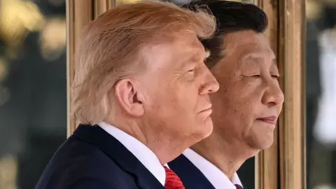 US President Donald Trump (L) and China's President Xi Jinping stand for their countries' national anthems during a welcome ceremony at the Great Hall of the People in Beijing on May 14, 2026. 