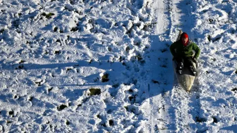 Getty Images A person sledges down a hill in a canoe near Dorchester following snowfall on 21 November 2024.