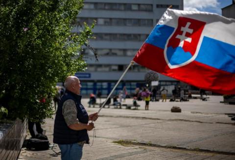 man waves slovak flag outside the hospital
