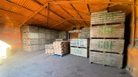 Luke Abblitt Stacks of potatoes inside a warehouse.