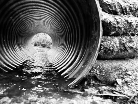Ali Lawrence Black and white image of water in a metal pipe
