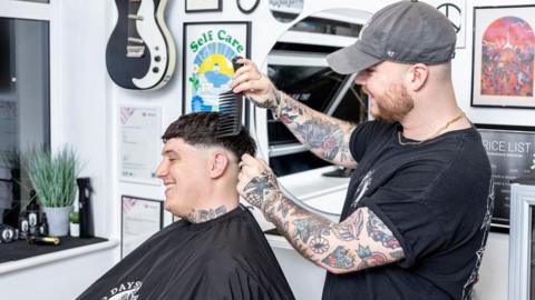Barber Jake Cox cuts a client's hair 