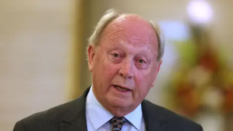 PA Media Mid-shot of Jim Allister, grey hair, black suit, blue tie, white shirt