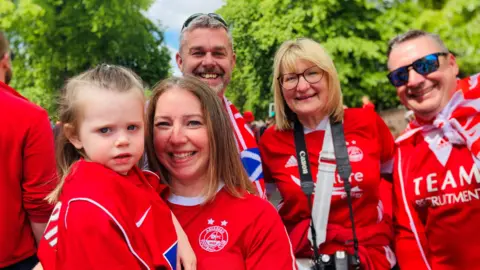 Young girl dressed in red with other family members also in red, all smiling.