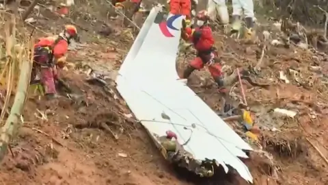 Rescue teams with a piece of the fuselage of China Eastern passenger jet 