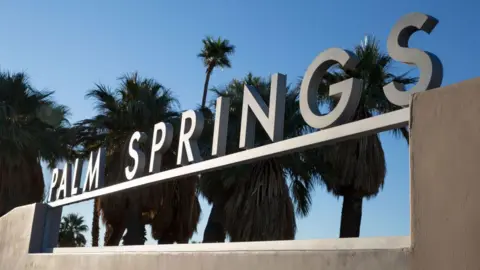 The main sign welcoming visitors to Palm Springs is shown against a blue sky