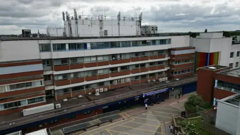 Steve Hubbard/BBC The outside of a five-storey hospital building with white and brown panelling.