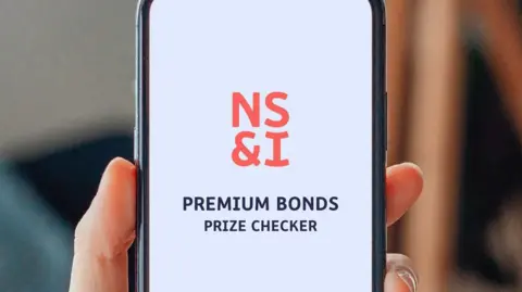 PA Media NS&I of Premium Bonds Prize Checker displayed on a phone. 