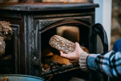 Getty Images Wood being placed in a stove