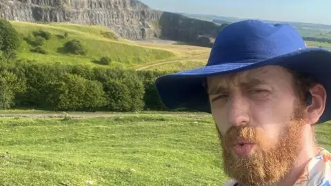 Richard Stennett wearing a hat, and blue top in the Peak District