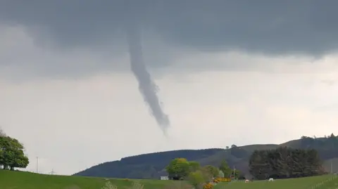 BBC Weather Watchers/Kas A landscape image of a funnel cloud that extends down from a cloud but does not reach as far as the ground