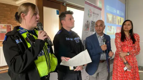 A line up of police and other advisors inside a community centre
