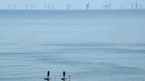 Two surfers look at the rampion farm in the sea