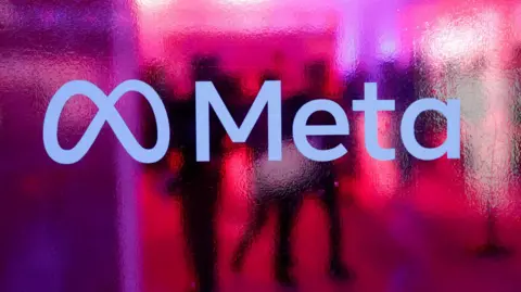 People walk behind a Meta Platforms logo during a conference in India in 2023