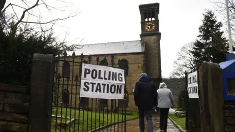 Two people pictured walking into a polling station at a church.