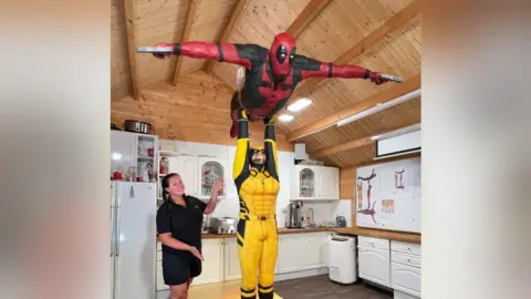 Lara Mason Baker Lara Mason smiled and points to her cake sculpture of Marvel superheros Deadpool and Wolverine, with Wolverine lifting Deadpool in the air in a recreation of the Dirty Dancing lift