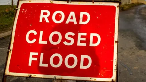 A red sign with the words road "closed flood" on it