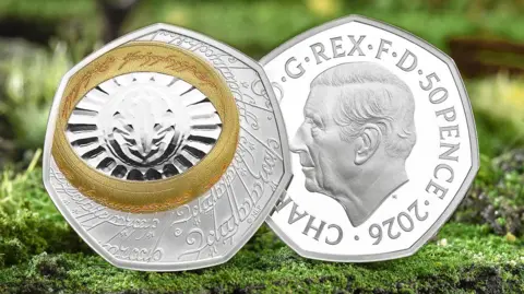 The Royal Mint Both sides of the coin shown on a fake background of granite grey rock frosted in green lichen. The back of the coin on the left is silver with an etching in a Lord of the Rings script and language. A gold band, the one ring, is also inscribed in an Tolkien language, and sits slightly to the top left corner of the seven sided coin. it surrounds the eye of sauron, a slit etched onto the silver with an oval around it that is then surrounded by a fan of lines to the ring, making it look like the sun. the face of the coin, the right is the same as a 50p coin with a King Charles the third profile and the visible inscription fromt he top clockwise of G Rex F D 50 pence 2026 Char with the rest of the king's name obstructed by the back of the coin. 