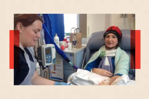 Victoria Derbyshire Victoria sits in a hospital chair receiving treatment, wearing a head covering and blanket.