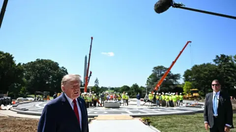 President Trump stands at the helipad construction site at the White House.