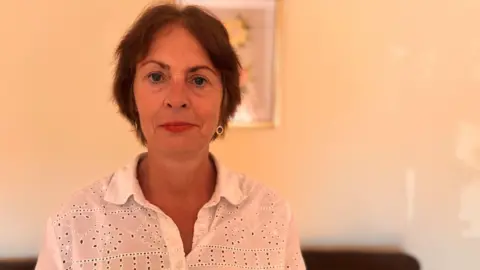A woman with brown hair and a white shirt