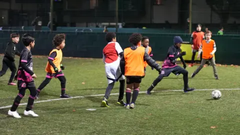 A group of children play football on a pitch