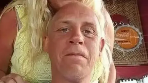 Lancashire Police handout Tony Johnson is smiling as he looks into the camera, with a woman standing behind him, whose face cannot be seen.