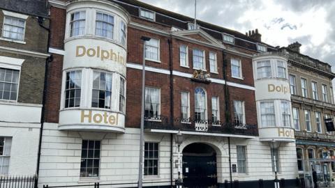 Front of Dolphin hotel white brick ground floor with arched gated entrance pair of bay windows on first and second floors