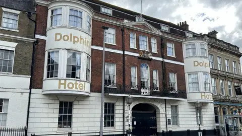 LDRS Front of Dolphin hotel white brick ground floor with arched gated entrance pair of bay windows on first and second floors