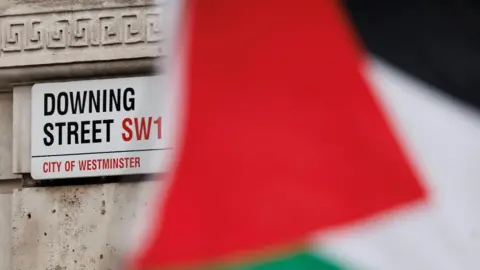 Getty Images A Palestinian flag flies in front of a road sign reading Downing Street, SW1