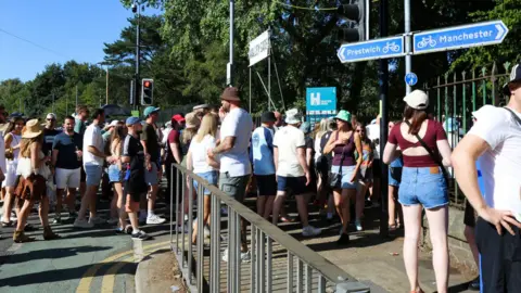 Emma Gibbs Dozens of Oasis fans in bucket hats, T-shirts and shorts walk through the entrance into Heaton Park ahead of the band's gig at the site
