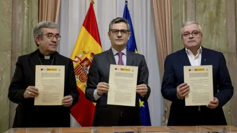 The three officials holding the agreement they signed in from of them