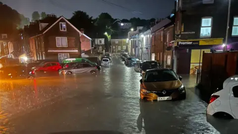 Cars are submerged in flood water on a residential street. 