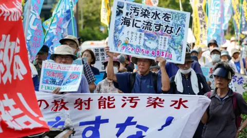 Demonstran EPA memegang plakat selama protes terhadap pelepasan air limbah radioaktif yang diolah oleh pembangkit listrik tenaga nuklir Fukushima Daiichi ke laut dekat markas Tepco di Tokyo, Jepang, 20 Juli 2023.