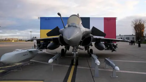 A grey storm shadow missile is pictured next to a fighter jet