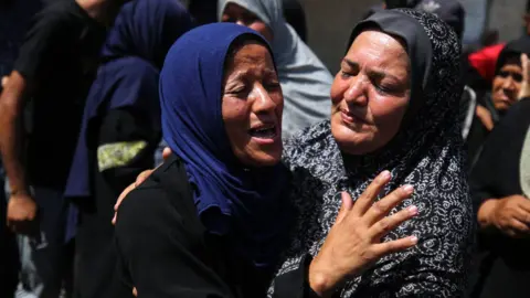 Palestinian women mourn as the bodies of the Palestinians killed in the Israeli attack are brought to the morgue of Al-Aqsa Martyrs Hospital in Deir al-Balah, Gaza