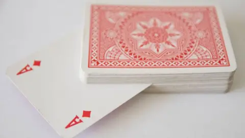 A pack of playing cards, with an ace poking out