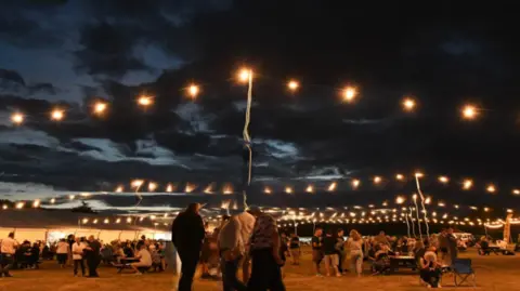 Peterborough Beer Festival  Fairy lights alongside a marquee with people on benches drinking beer