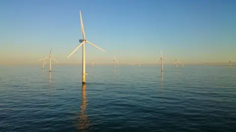 Equinor Wind turbines at Sheringham Shoal rising out of the water against a hazy blue sky