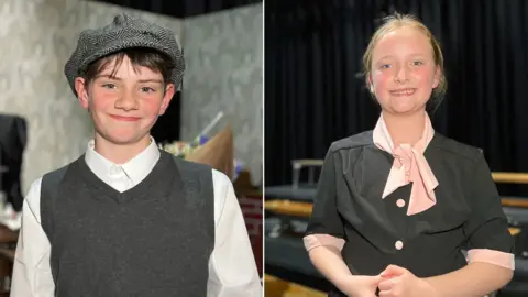Cameron and Mia are wearing 1940s-style clothes as they smile at the camera