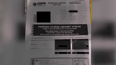Dipti Tait The image shows a black‑and‑white parking ticket featuring two small photos of the car entering and leaving the car park. A large black box on the notice displays the text: "Parking Charge Amount: £100.00".