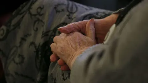 Elderly woman sat with her hands closed together